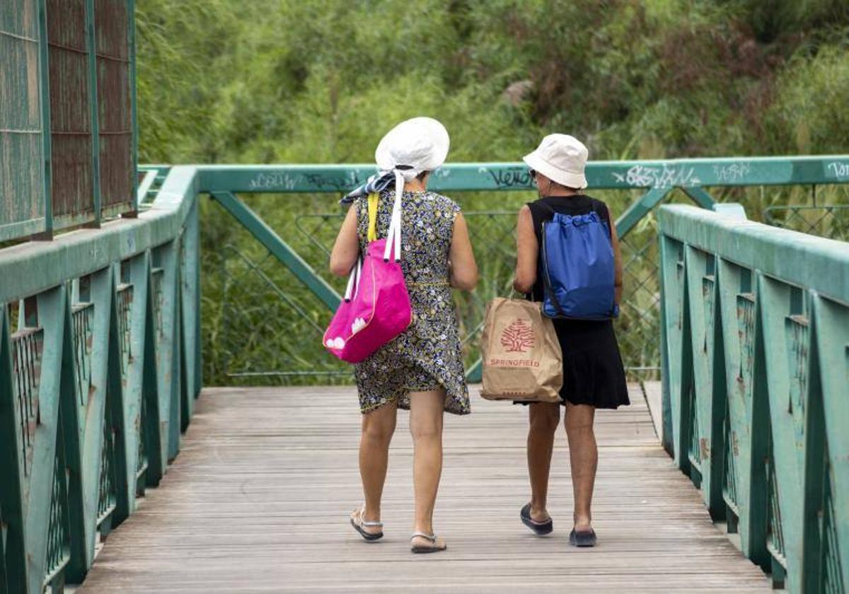 Dos señoras, con vestidos primaverales y chanclas, por Alicante.