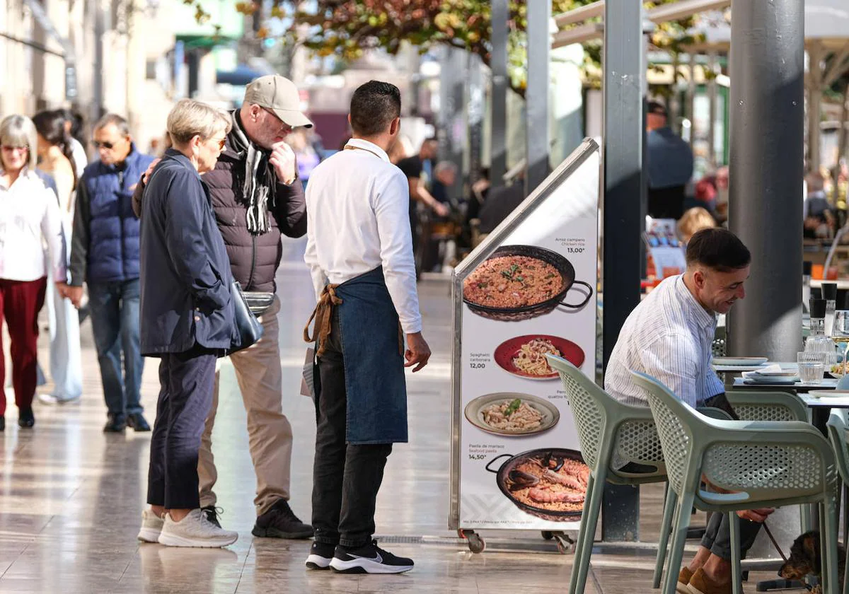 Unos turistas miran el menú de un restaurante de la Explanada.