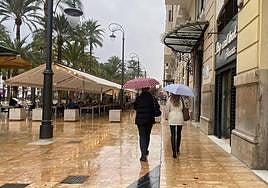Dos mujeres pasena por la Explanada con paraguas.