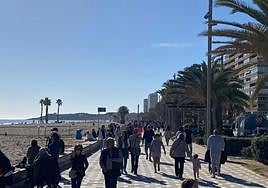 Alicantinos pasean por la playa de San Juan durante un día de verano en enero.
