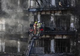Los bomberos inspeccionan la fachada principal de los edificios incendiados.