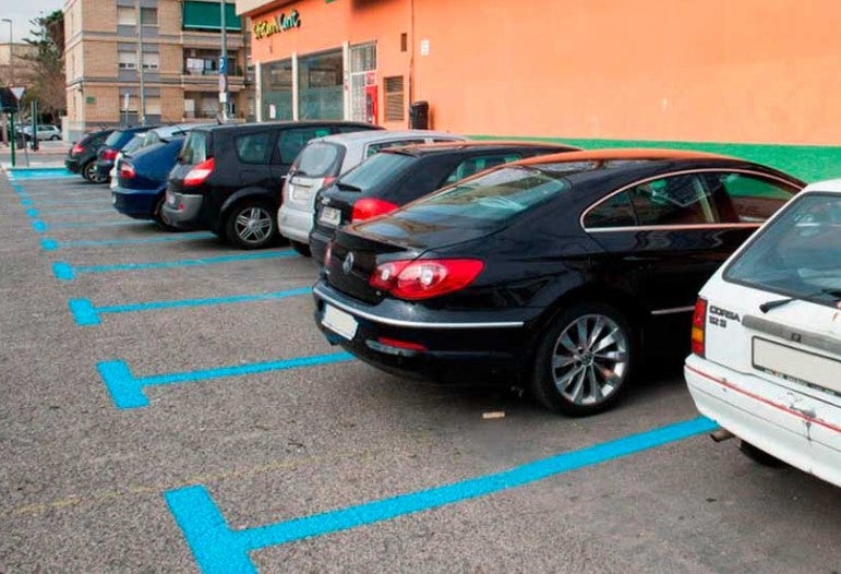 Varios coches aparcados en zona azul.