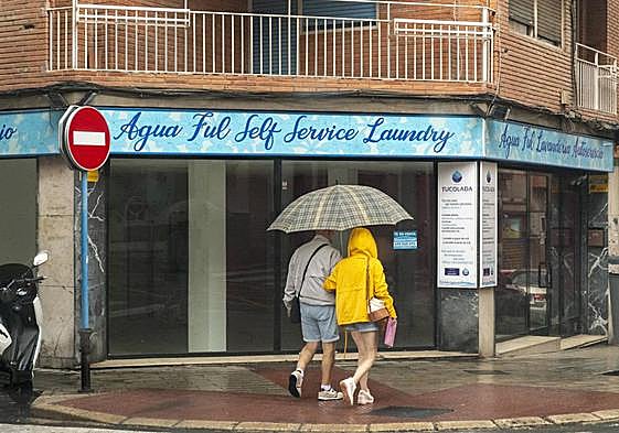 Dos personas se refugian de la lluvia bajo un paraguas.