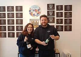 Los fundadores, Jorge y Mayte posan con cervezas delante de la pared que exhibe los premios conseguidos.