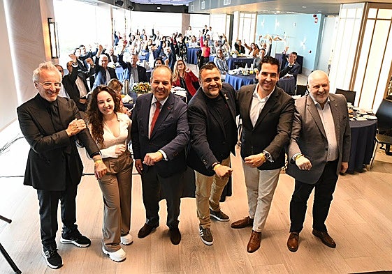 Los participantes en el desayuno muestras sus pulseras en solidaridad con la lucha contra el cáncer infantil.