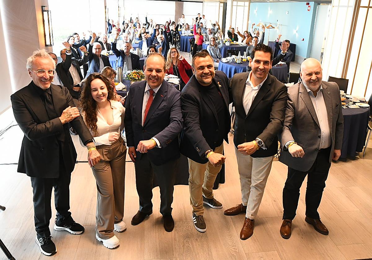 Los participantes en el desayuno muestras sus pulseras en solidaridad con la lucha contra el cáncer infantil.