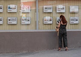 Una mujer consulta los anuncios de pisos en una imobiliaria.