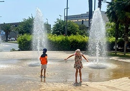 Dos niños se refrescan en una fuente de Alicante.