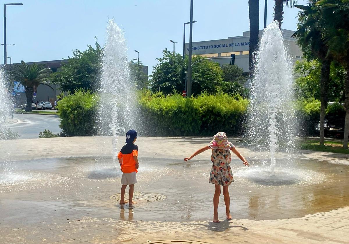 Dos niños se refrescan en una fuente de Alicante.