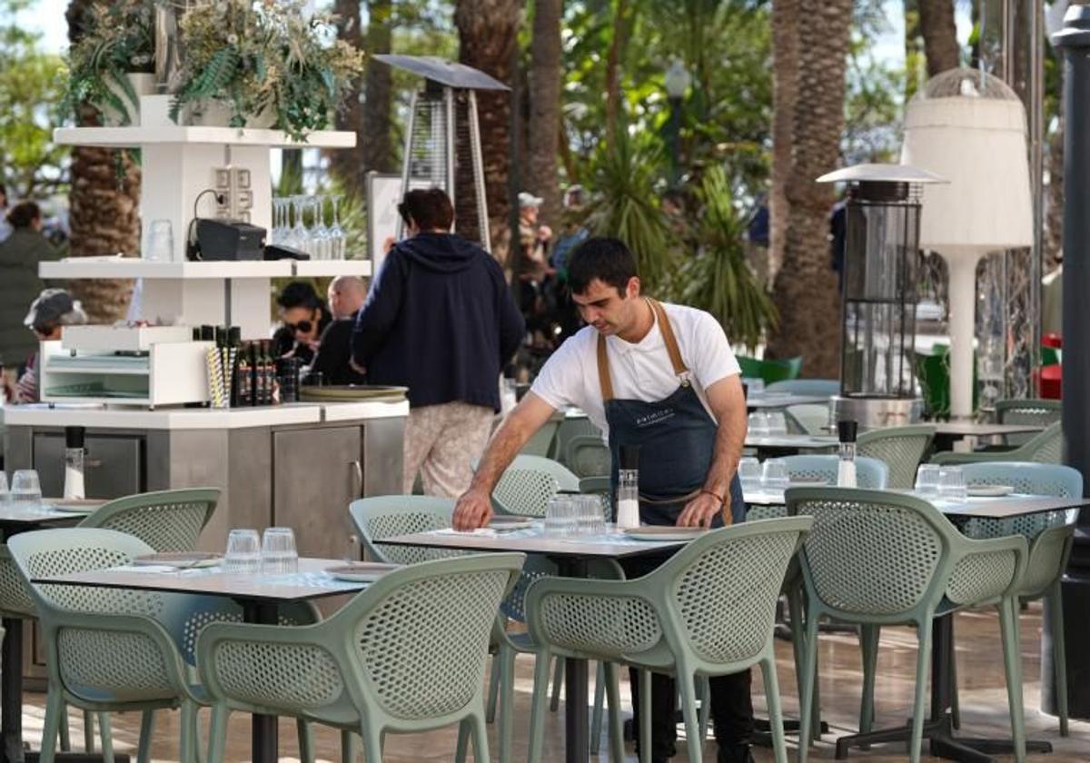 Un camarero prepara una mesa en la Explanada para el servicio de comida.