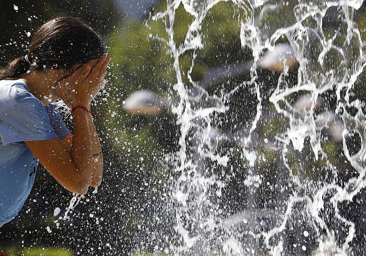 Una mujer se refresca en una fuente.