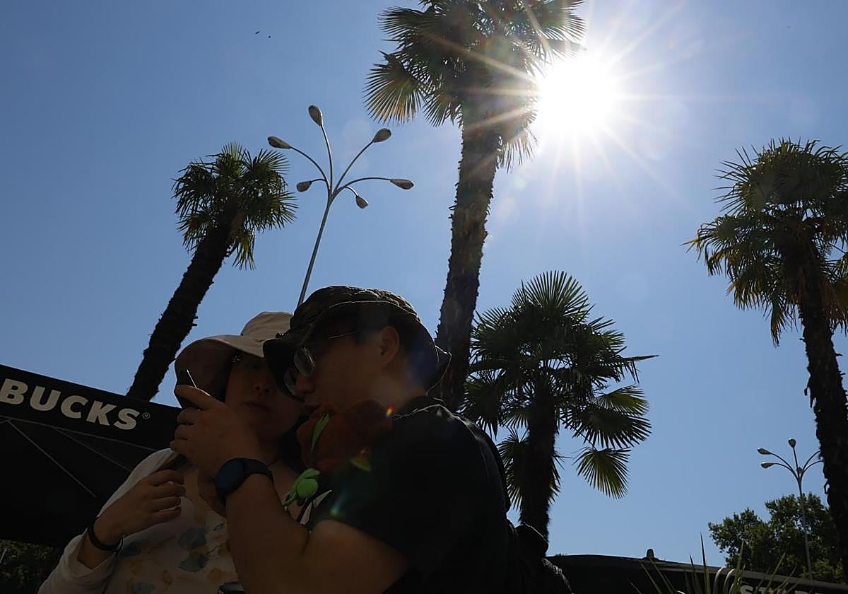 Varios turistas pasean bajo el sol.