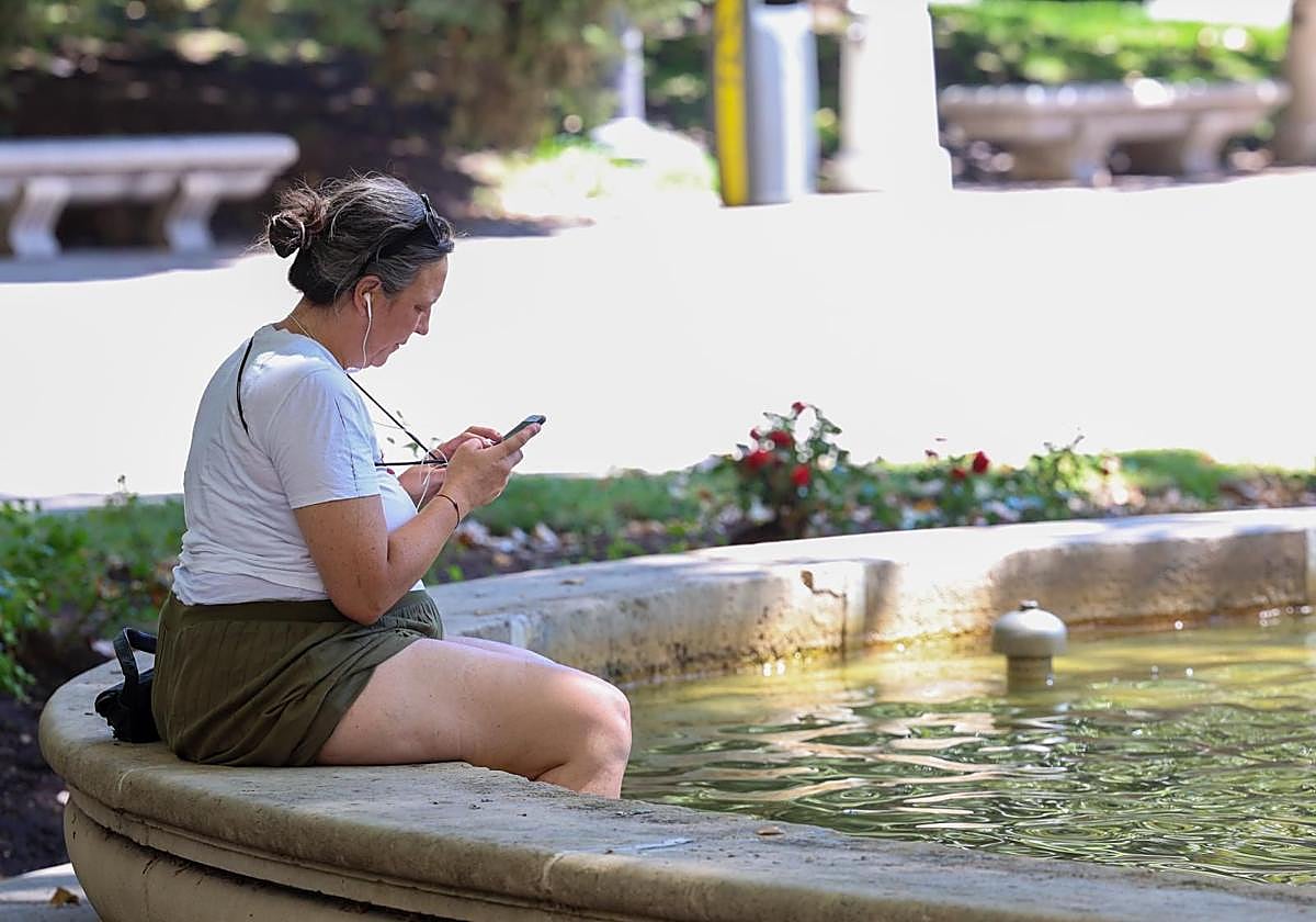 Una mujer con los pies metidos en una fuente.