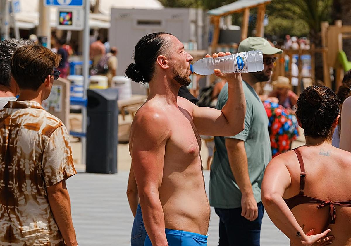 Un ciudadano se hidrata en el paseo de la playa del Postiguet para combatir las altas temperaturas.