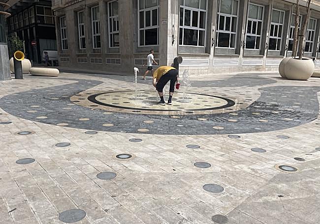 Persona refrescándose en una de las fuentes de La Explanada de Alicante.
