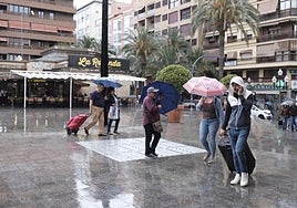 Transeúntes se protegen de la lluvia este martes en Alicante.