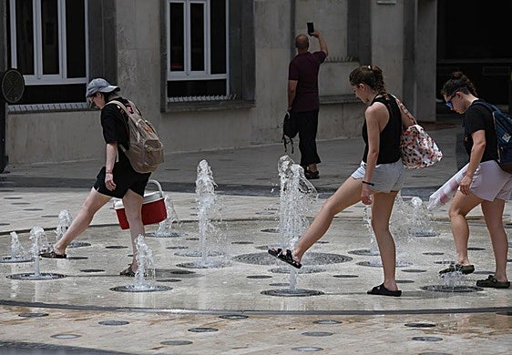 Turistas se refrescan los pies en la fuente de la Explanada con Rambla de Méndez Núñez.