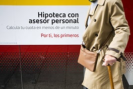 Una persona pasea frente a un cartel aunciando hipotecas en una entidad bancaria.