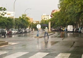 Un hombre se protege de la lluvia en Alicante.