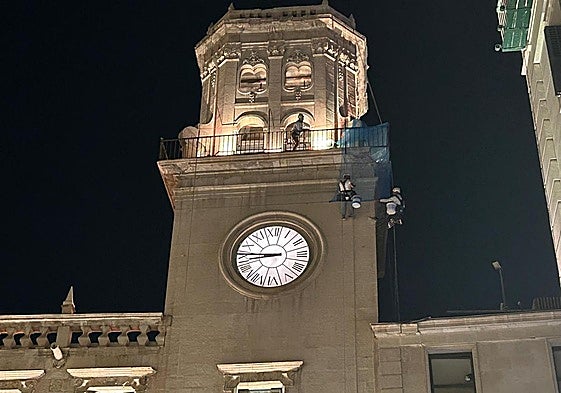 Operarios colocan una malla en la Torre del Reloj del Ayuntamiento de Alicante.
