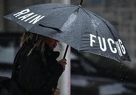 Una mujer se protege de la lluvia con un paraguas.