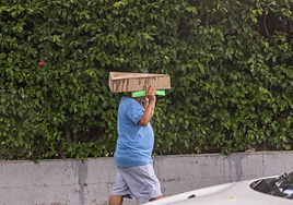Un ciudadano se protege de la lluvia en Alicante con un cartón.