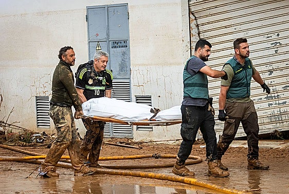 Miembros de la Guardia Civil trasladan un cadáver en la zona afectada.