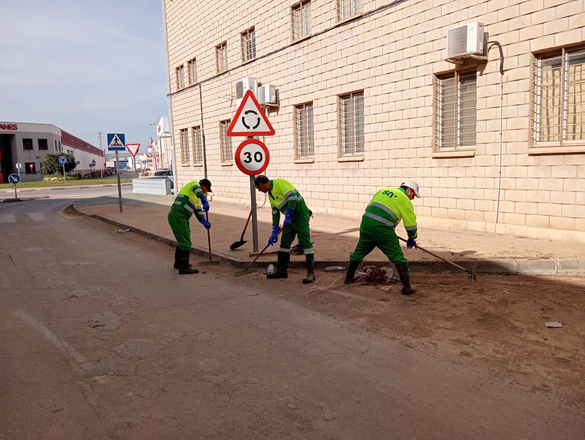 Limpieza de un vial por parte de operarios, que retiran lodo.