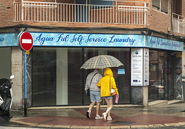 Dos viandantes se protegen de la lluvia en Alicante.