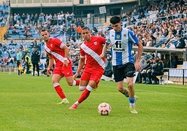 Retu avanza ante dos jugadores del Sevilla Atlético.