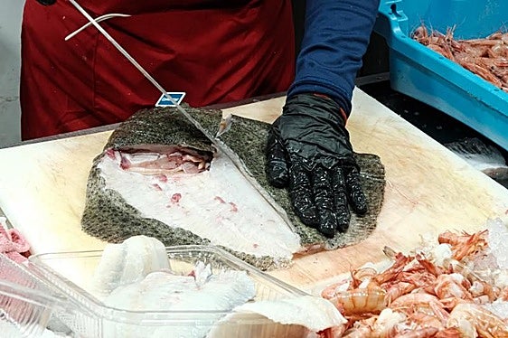 Un pescadero prepara un rodaballo, en el Mercado Central de Alicante.