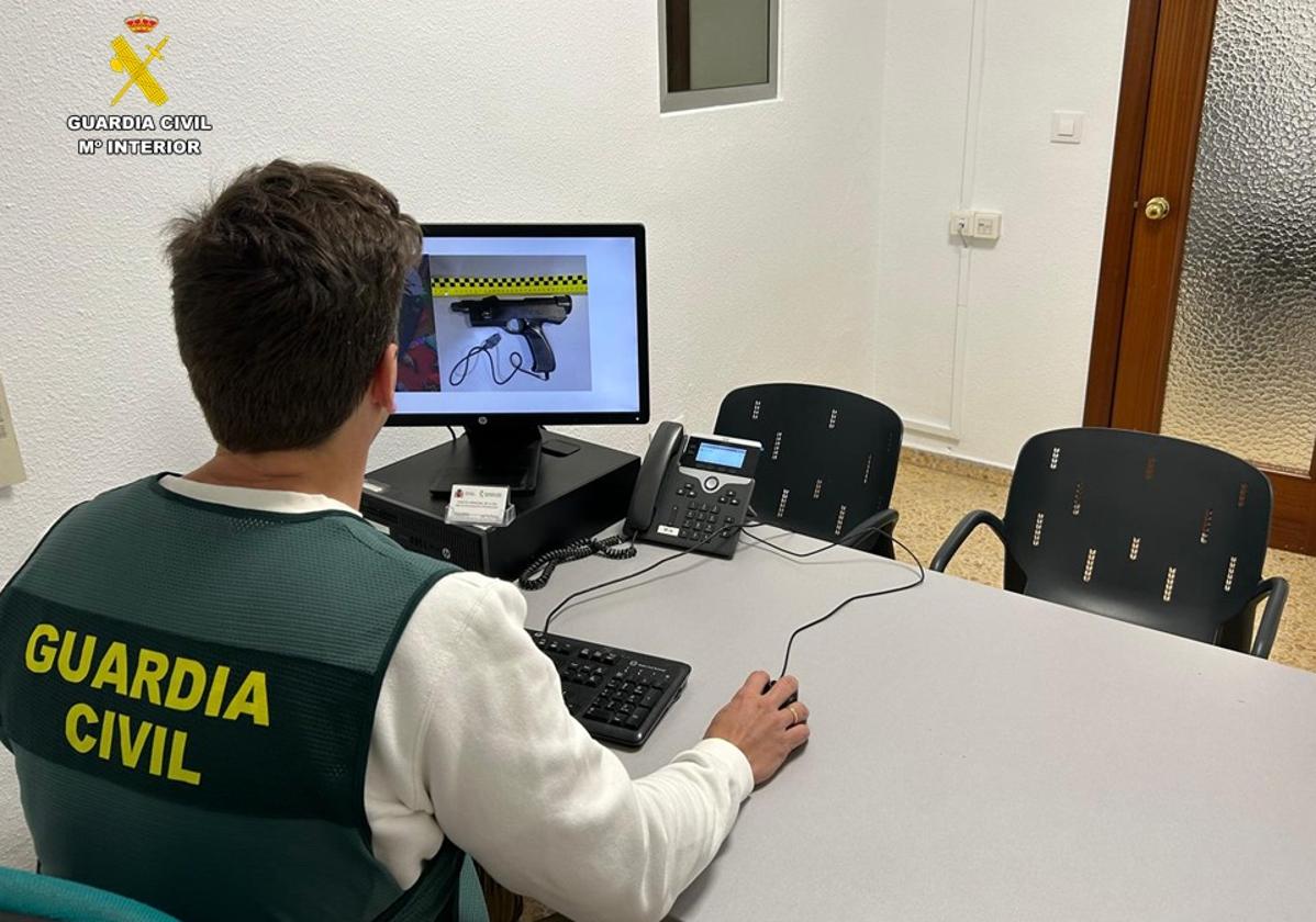 Un investigador observa imágenes de la pistola de plástico utilizada por los ladrones en el robo.
