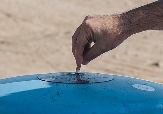Un fumador apaga su cigarrillo en una papelera.