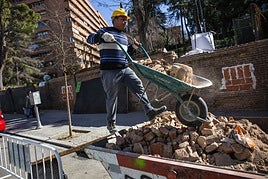 Un albañil deposita escombros en un contenedor de obra.