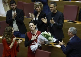 Aitana Mas recibe emocionada un ramo de flores del síndic de Compromís, Joan Baldoví, y el aplauso de sus compañeros de partido.
