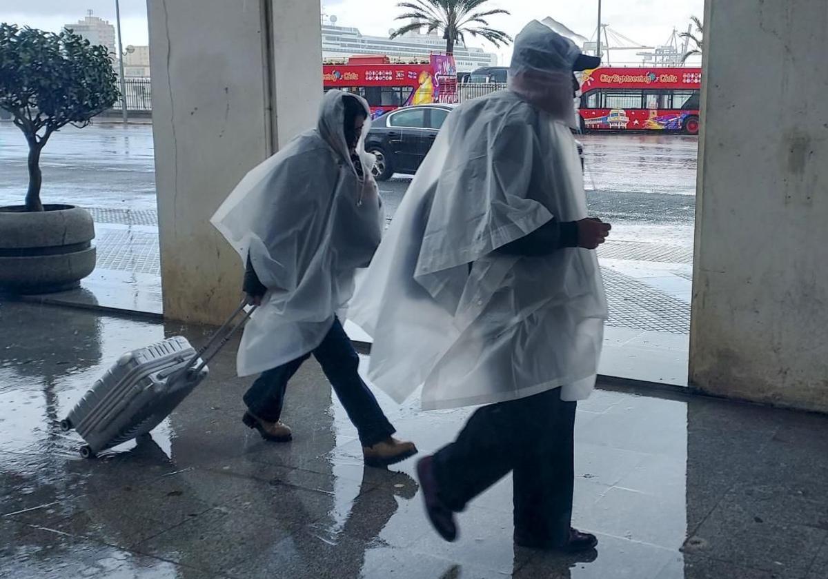 Two people shield themselves from the rain.