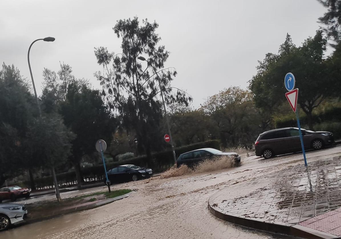 Un coche atraviesa la corriente de agua que baja del parque.