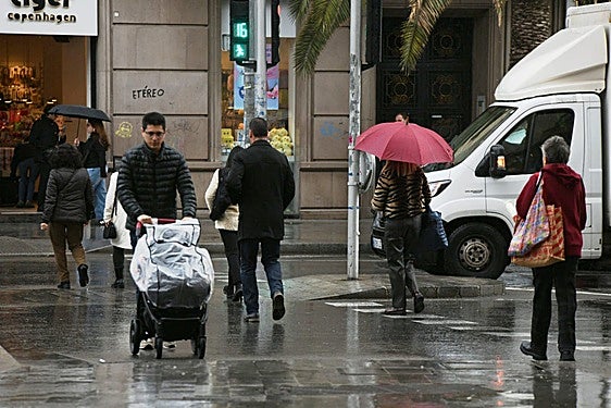 Personas pasean por Alicante bajo la lluvia.