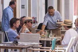 Un camarero atiende a varios turistas en un bar.