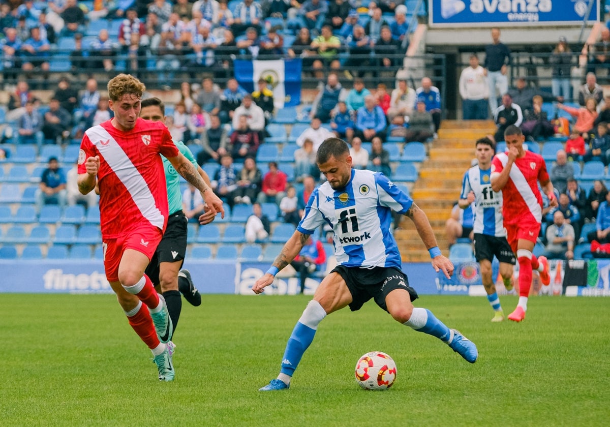 Artiles shields the ball from a Sevilla Atlético player.