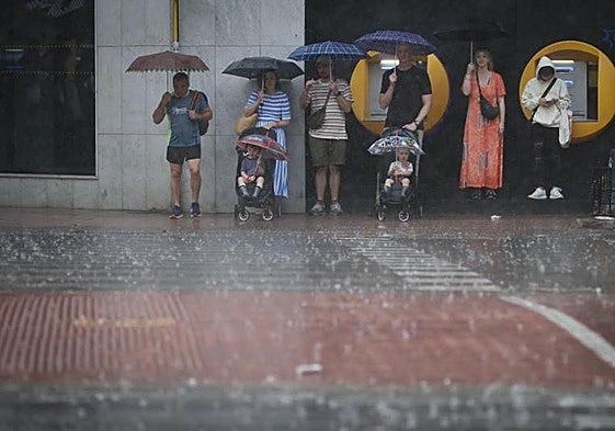 Unas personas se refugian del granizo caído en mitad de la calle.
