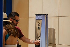 Una persona rellena su botella de agua en una fuente del Postiguet.