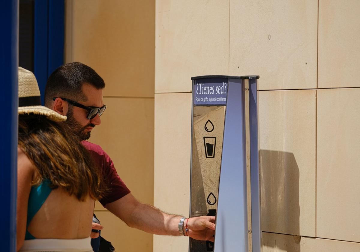 Una persona rellena su botella de agua en una fuente del Postiguet.