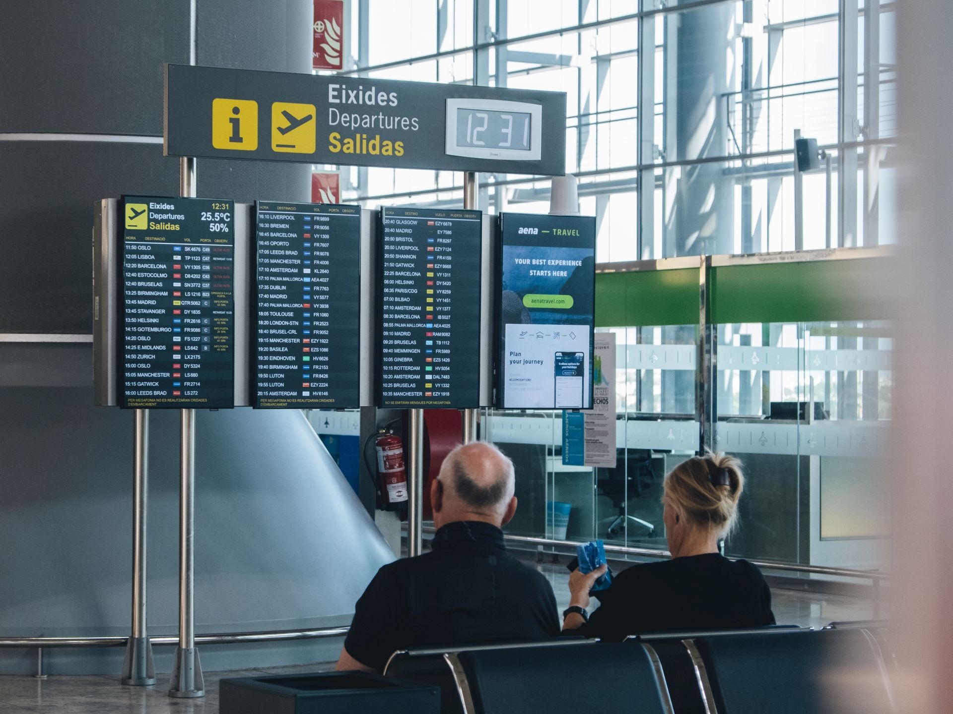 Two tourists look at the flight board.