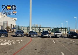 Un agente de la Policía Nacional junto a los vehículos robados decomisados en el Puerto de Alicante.