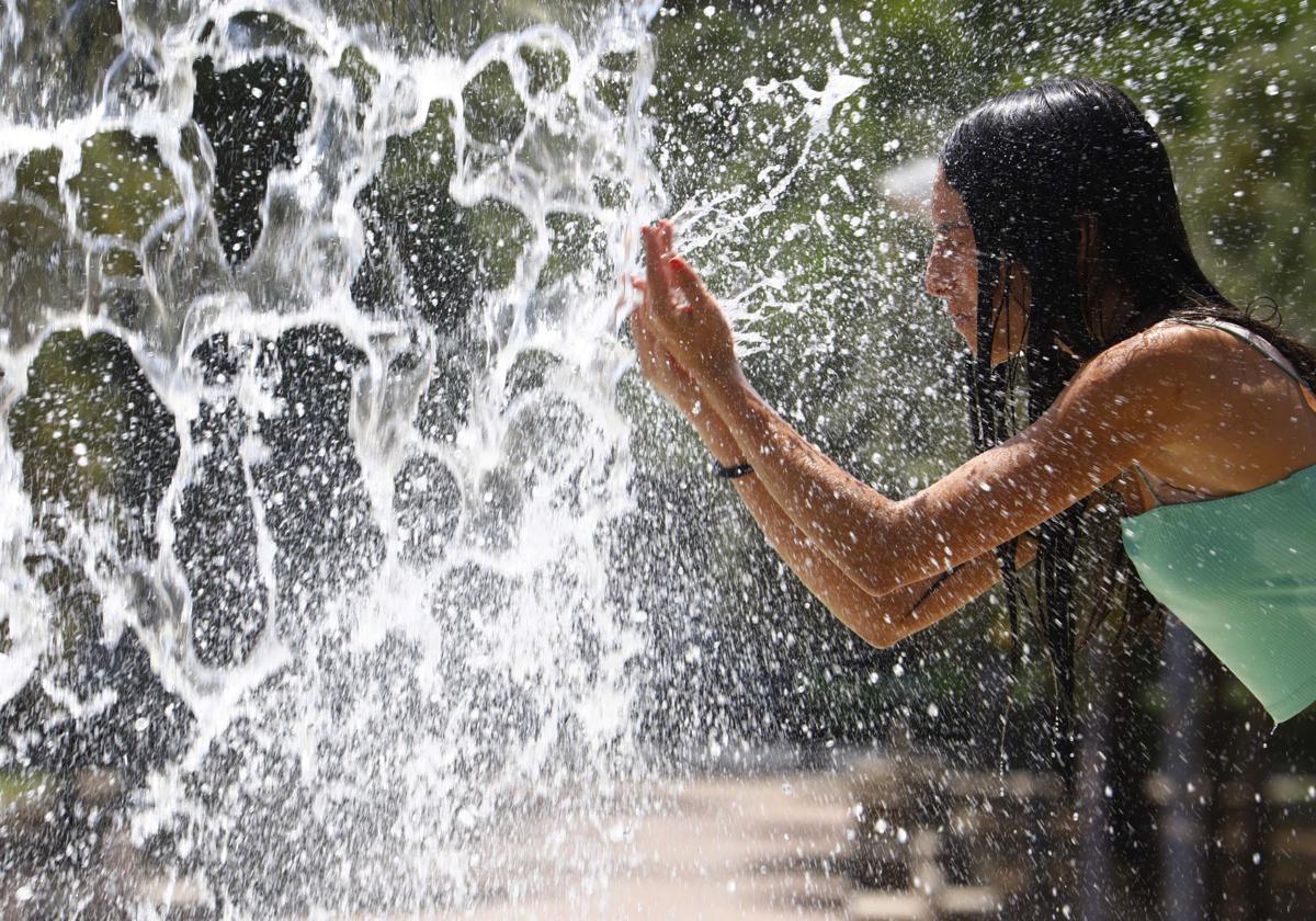 Chica refrescándose en una fuente
