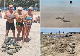 Varias personas recogen piedras en el Postiguet.