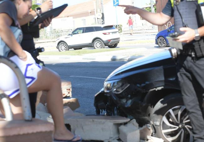 Los agentes examinan los daños del coche y del muro para el atestado.