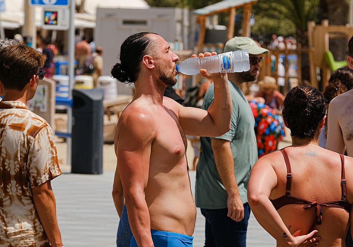 Una persona se refresca con agua fría en la playa del Postiguet de Alicante.