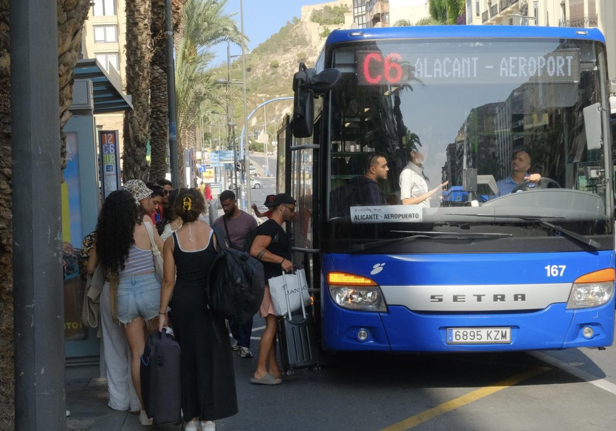 Turistas hacen cola en la parada del Mercado Central para coger el autobús del aeropuerto.